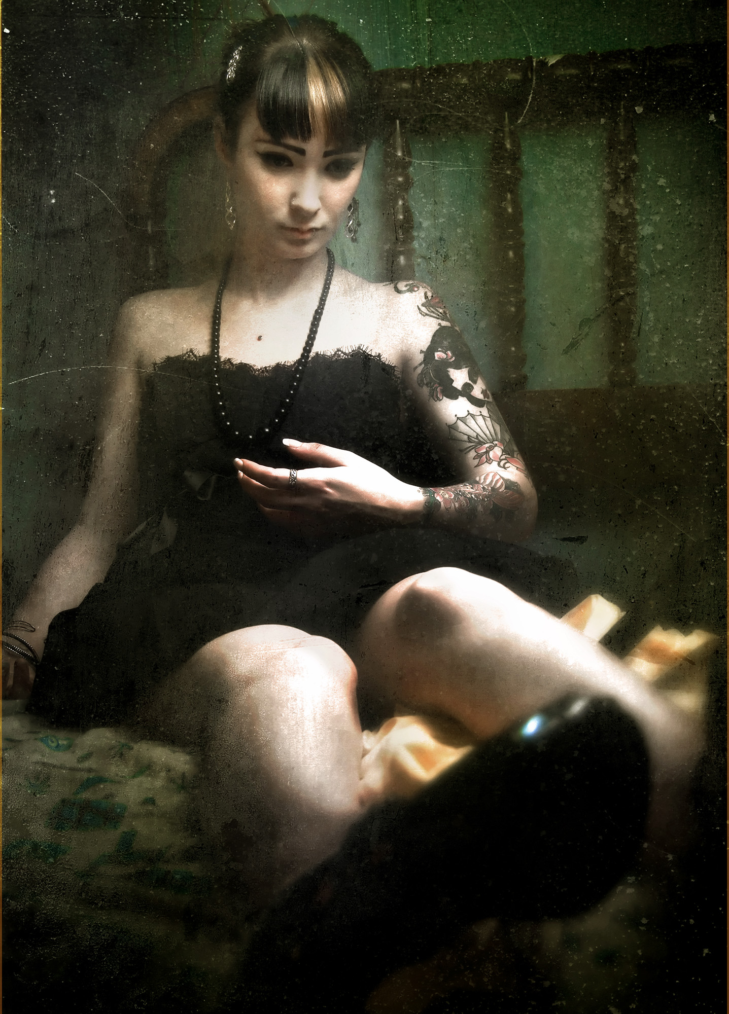 Broken: a tattooed woman in a black dress seated against a textured green background